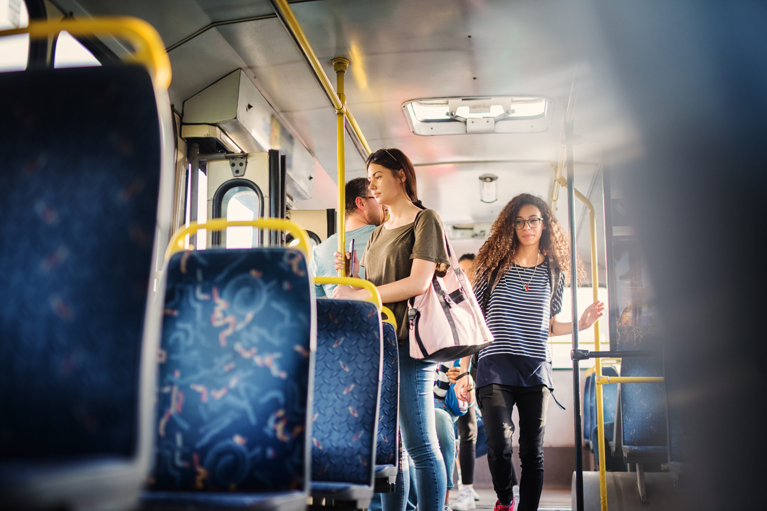 Lockiges Mädchen geht durch den Bus und versucht, einen freien Sitzplatz zu finden. Lockiges Mädchen geht durch den Bus und versucht, einen freien Sitzplatz zu finden.